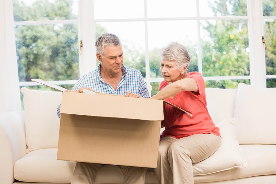 A senior couple packing a box together, symbolizing the transition to senior living