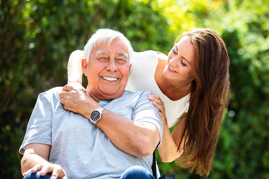 A smiling elderly man outdoors with a caregiver, illustrating a caring environment, the key to what to look for in a senior living community