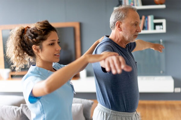 Care giver assisting senior man with balance exercise