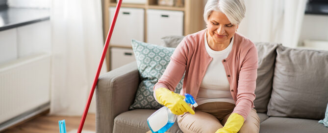 Senior woman happily engaged in spring cleaning, wiping a coffee table in her living room