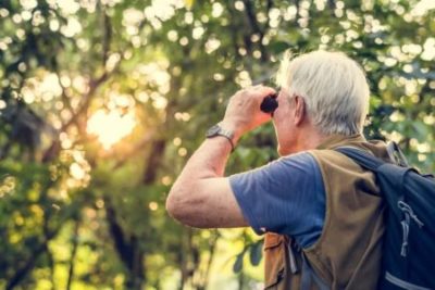 activities for seniors - a senior holding a telescope birdwatching